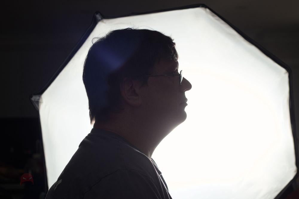 A man sits in front of an octagonal light source. He is facing to the right of the photo.