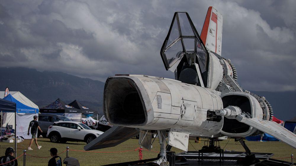 A futuristic space fighter sits on a platform in a field
